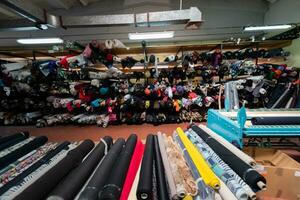 Innere von ein industriell Warenhaus mit Stoff Rollen Proben. klein Geschäft Textil- bunt Lagerhaus. foto