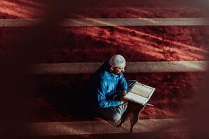 ein Muslim liest das heilig islamisch Buch Koran im ein modern großartig Moschee während das Muslim heilig Monat von ranazan foto