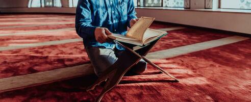ein Muslim liest das heilig islamisch Buch Koran im ein modern großartig Moschee während das Muslim heilig Monat von ranazan foto