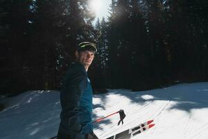 Porträt gut aussehend männlich Athlet mit Kreuz Land Ski im Hände und Brille, Ausbildung im schneebedeckt Wald. gesund Winter Lebensstil Konzept. foto