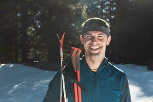 Porträt gut aussehend männlich Athlet mit Kreuz Land Ski im Hände und Brille, Ausbildung im schneebedeckt Wald. gesund Winter Lebensstil Konzept. foto