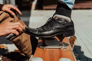 ein alt Mann Hand Polieren und Gemälde ein schwarz Schuh beim Straße foto