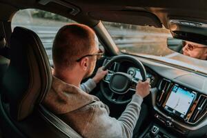 ein Mann mit ein Sonnenbrille Fahren ein Auto beim Sonnenuntergang. das Konzept von Auto Reise foto