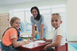 kreativ Kinder während ein Kunst Klasse im ein Kindertagesstätte Center oder elementar Schule Klassenzimmer Zeichnung mit weiblich Lehrer. foto