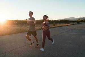 gesund jung Paar Joggen im das Stadt Straßen im das früh Morgen mit ein schön Sonnenaufgang im das Hintergrund. foto