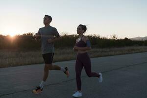 gesund jung Paar Joggen im das Stadt Straßen im das früh Morgen mit ein schön Sonnenaufgang im das Hintergrund. foto