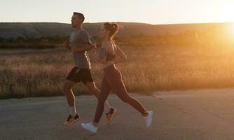 gesund jung Paar Joggen im das Stadt Straßen im das früh Morgen mit ein schön Sonnenaufgang im das Hintergrund. foto