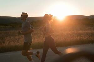 gesund jung Paar Joggen im das Stadt Straßen im das früh Morgen mit ein schön Sonnenaufgang im das Hintergrund. foto