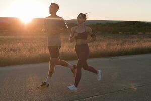 gesund jung Paar Joggen im das Stadt Straßen im das früh Morgen mit ein schön Sonnenaufgang im das Hintergrund. foto