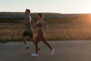 gesund jung Paar Joggen im das Stadt Straßen im das früh Morgen mit ein schön Sonnenaufgang im das Hintergrund. foto