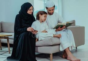 glücklich Muslim Familie genießen das heilig Monat von Ramadan während beten und lesen das Koran zusammen im ein modern Zuhause foto