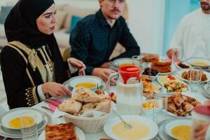 Muslim Familie haben iftar Abendessen Trinken Wasser zu brechen Fest. Essen traditionell Essen während Ramadan schlemmen Monat beim heim. das islamisch halal Essen und Trinken im modern Zuhause foto