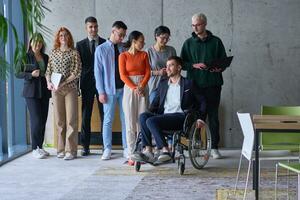 vielfältig Gruppe von Geschäft Menschen, einschließlich ein Geschäftsmann im ein Rollstuhl im ein modern Büro foto
