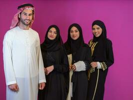 Gruppe Porträt von jung Muslim Menschen arabisch Mann mit drei Muslim Frauen im modisch Kleid mit Hijab isoliert auf Rosa Hintergrund Darstellen modern Islam Mode und Ramadan kareem Konzept foto