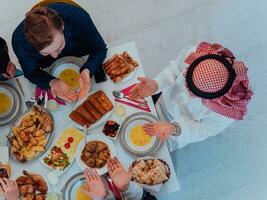 oben Aussicht von Muslim Familie haben iftar Abendessen Trinken Wasser zu brechen Fest. Essen traditionell Essen während Ramadan schlemmen Monat beim heim. das islamisch halal Essen und Trinken im modern Zuhause foto