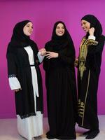 Gruppe Porträt von schön Muslim Frauen zwei von Sie im modisch Kleid mit Hijab isoliert auf Rosa Hintergrund Darstellen modern Islam Mode und Ramadan kareem Konzept foto