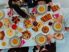 oben Aussicht von Muslim Familie haben iftar Abendessen Trinken Wasser zu brechen Fest. Essen traditionell Essen während Ramadan schlemmen Monat beim heim. das islamisch halal Essen und Trinken im modern Zuhause foto