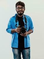 Fachmann Fotograf haben dslr Kamera nehmen Bild.indisch Mann Fotografie Enthusiast nehmen Foto während Stehen auf Blau Hintergrund. Studio Schuss