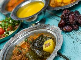 eid Mubarak traditionell Ramadan iftar Abendessen. sortiert lecker Essen im authentisch rustikal Geschirr auf hölzern Blau Hintergrund. Türkisch bosnisch Essen Fleisch Kebab, Pita-Brot, Sarma, Klepe, sogan Dolma. foto