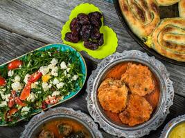 eid Mubarak traditionell Ramadan iftar Abendessen. sortiert lecker Essen im authentisch rustikal Geschirr auf hölzern Blau Hintergrund. Türkisch bosnisch Essen Fleisch Kebab, Pita-Brot, Sarma, Klepe, sogan Dolma. foto