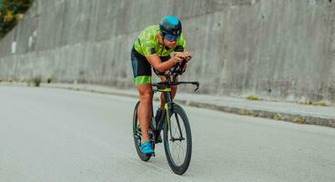 voll Länge Porträt von ein aktiv Triathlet im Sportbekleidung und mit ein schützend Helm Reiten ein Fahrrad. selektiv Fokus foto