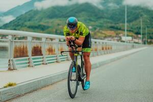 voll Länge Porträt von ein aktiv Triathlet im Sportbekleidung und mit ein schützend Helm Reiten ein Fahrrad. selektiv Fokus foto