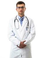 Porträt von Held im Weiß Mantel. heiter lächelnd jung Arzt mit Stethoskop im medizinisch Krankenhaus Stehen gegen Weiß Hintergrund. Coronavirus covid-19 Achtung warnen foto