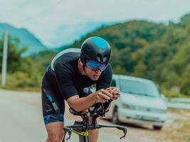 voll Länge Porträt von ein aktiv Triathlet im Sportbekleidung und mit ein schützend Helm Reiten ein Fahrrad. selektiv Fokus foto