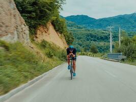 voll Länge Porträt von ein aktiv Triathlet im Sportbekleidung und mit ein schützend Helm Reiten ein Fahrrad. selektiv Fokus foto