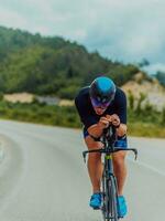 voll Länge Porträt von ein aktiv Triathlet im Sportbekleidung und mit ein schützend Helm Reiten ein Fahrrad. selektiv Fokus foto