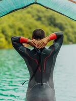 Athlet Putten auf ein Schwimmen passen und vorbereiten zum Triathlon Schwimmen und Ausbildung im das Fluss umgeben durch natürlich Grün foto