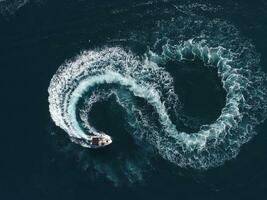 Antenne oben Aussicht von ein Weiß Vergnügen Boot auf ein Sommer- Tag. Motorboot Wende Schleife acht auf das Meer Herstellung Unendlichkeit Zukunft Konzept. foto