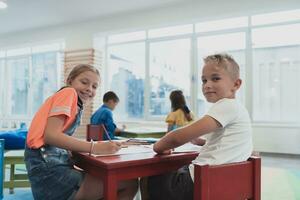 süß Mädchen und Junge sitzen und zeichnen zusammen im Vorschule Institution foto