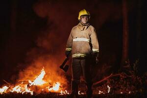 Feuerwehrmann beim Arbeit. Feuerwehrmann im gefährlich Wald Bereiche umgeben durch stark Feuer. Konzept von das Arbeit von das Feuer Bedienung foto