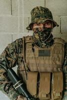 ein Soldat im Uniform steht im Vorderseite von ein Stein Mauer im voll Krieg Ausrüstung vorbereiten zum Schlacht foto