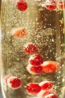 Sekt im Glas mit roten Johannisbeeren foto