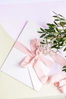 Umschlag auf weiß-rosa Hintergrund mit pfirsichfarbenem Seidenband foto