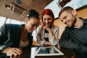 Geschäft Menschen im formal tragen Sitzung Kaffee und Analysieren Daten. auf Schreibtisch sind Laptops, Grafiken, Tablets und Papierkram. foto