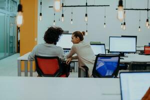 zwei Kollegen Arbeiten auf ein Projekt im modern Anfang Büros. Kerl mit afro Haarschnitt und ein weiblich blond Mitarbeiter Arbeiten beim das Büro. foto