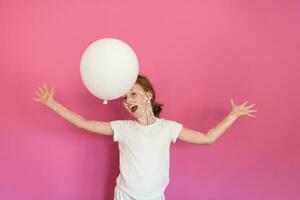 Porträt von ein wenig Schule Mädchen mit Windpocken, Antiseptikum Sahne angewendet zu Gesicht und Körper. spielen mit ein Weiß Ballon. Gesundheit Pflege und medizinisch Konzept. Rosa Hintergrund foto