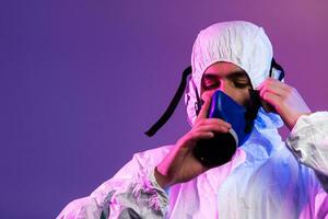 Coronavirus covid-19 Pandemie. Arzt Wissenschaftler tragen schützend biologisch passen und Maske fällig zu global Gesundheitswesen Epidemie Warnung und Achtung Hintergrund im Blau und Rosa Neon- Beleuchtung Hintergrund. foto