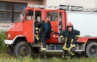 Gruppe von Feuer Kämpfer Stehen zuversichtlich nach ein Gut erledigt Rettung Betrieb. Feuerwehrmänner bereit zum Notfall Service. foto