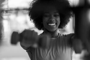 Frau, die in einem Crossfit-Fitnessstudio mit Hanteln trainiert foto