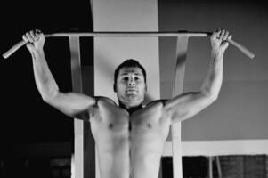 junger Mann mit starken Armen, der im Fitnessstudio trainiert foto