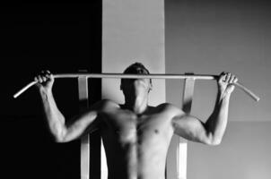 junger Mann mit starken Armen, der im Fitnessstudio trainiert foto