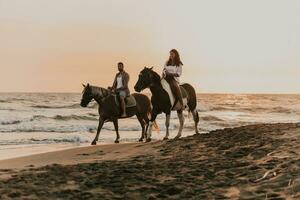 Ein liebevolles Paar in Sommerkleidung, das bei Sonnenuntergang an einem Sandstrand reitet. Meer und Sonnenuntergang im Hintergrund. selektiver Fokus foto