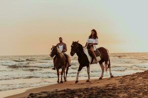 Ein liebevolles Paar in Sommerkleidung, das bei Sonnenuntergang an einem Sandstrand reitet. Meer und Sonnenuntergang im Hintergrund. selektiver Fokus foto