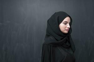 Porträt von schön Muslim Frau im modisch Kleid mit Hijab im Vorderseite von schwarz Tafel Darstellen modern Islam Mode und Ramadan kareem Konzept foto