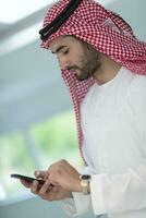 jung modern Muslim arabisch Geschäftsleute tragen traditionell Kleider während mit Smartphones beim heim. hohe Qualität Foto