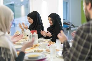 muslimische familie, die iftar dua macht, um während des ramadan das fasten zu brechen. foto